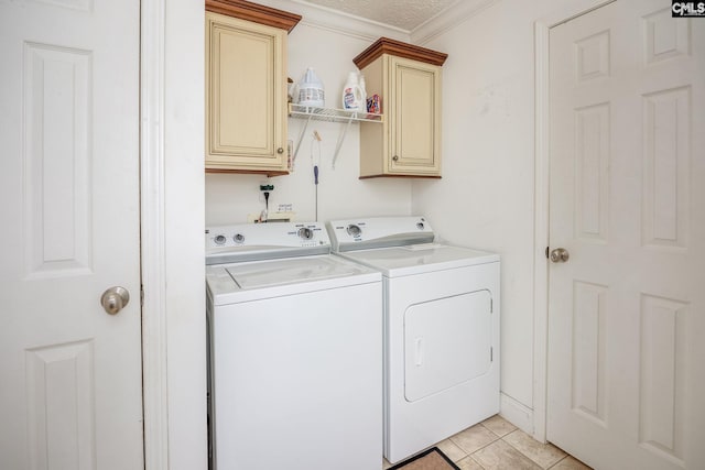 clothes washing area with washer and clothes dryer, cabinets, ornamental molding, and light tile floors