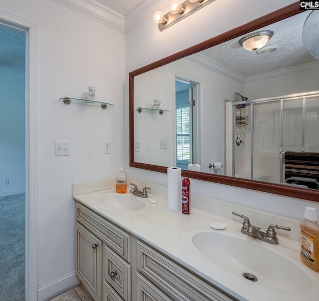 bathroom with a shower with shower door, a textured ceiling, crown molding, and double sink vanity