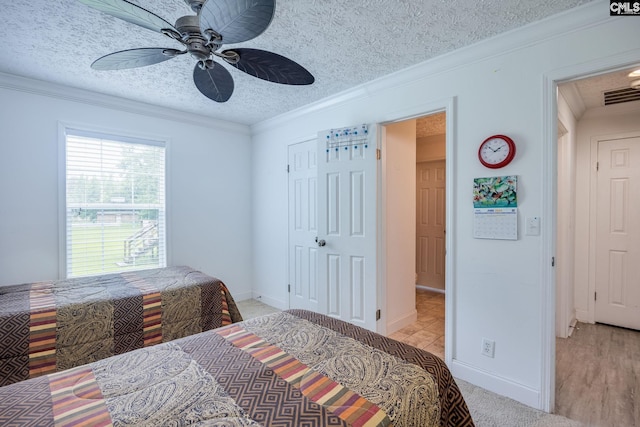 bedroom featuring light wood-type flooring, ceiling fan, a textured ceiling, and crown molding