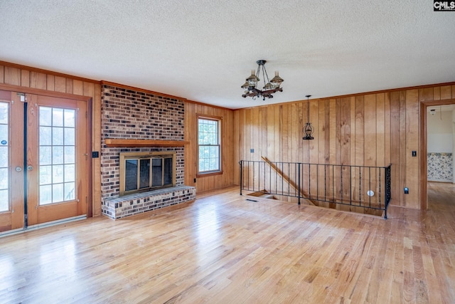 unfurnished living room with brick wall, wood-type flooring, wooden walls, and a textured ceiling