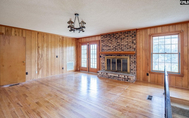 unfurnished living room with wood walls, plenty of natural light, and light hardwood / wood-style flooring