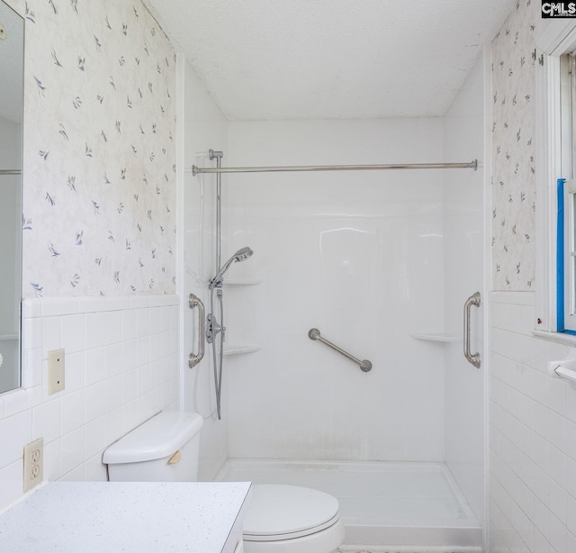 bathroom with tile walls, an enclosed shower, vanity, and toilet