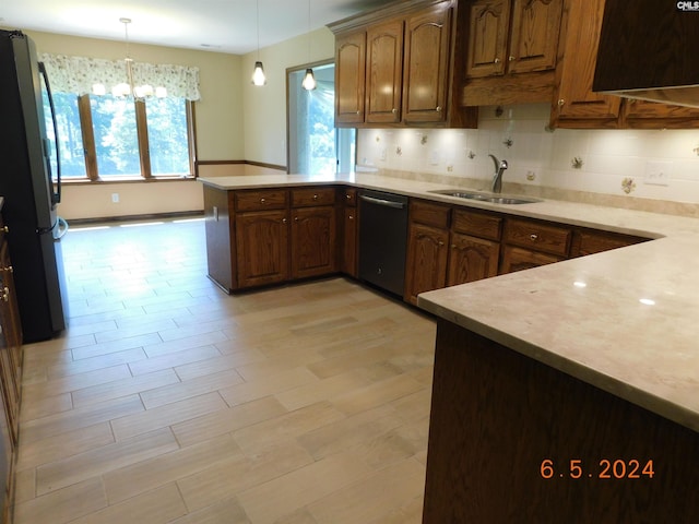 kitchen featuring kitchen peninsula, stainless steel dishwasher, hanging light fixtures, and sink