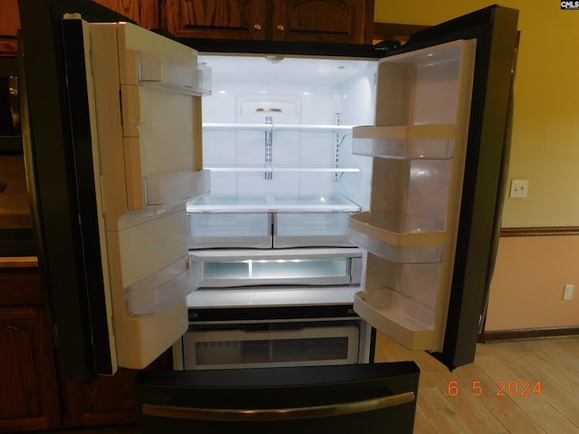 interior details featuring dark brown cabinets, refrigerator, and light hardwood / wood-style flooring