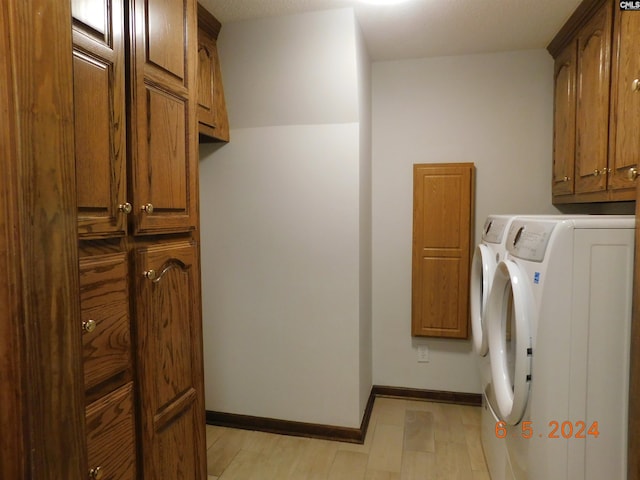 clothes washing area with cabinets and washing machine and dryer