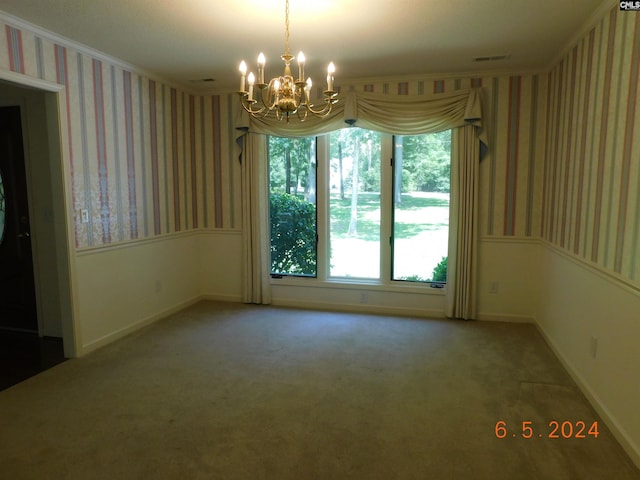 spare room with crown molding, carpet floors, and an inviting chandelier