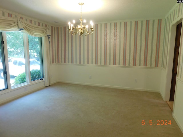 carpeted empty room with an inviting chandelier