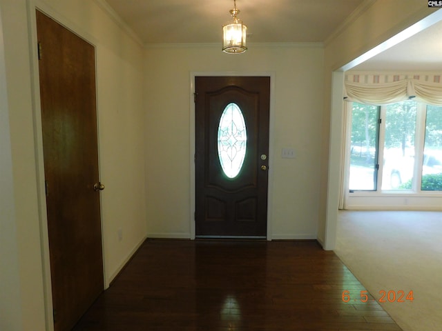 entryway featuring crown molding, dark wood-type flooring, and a notable chandelier