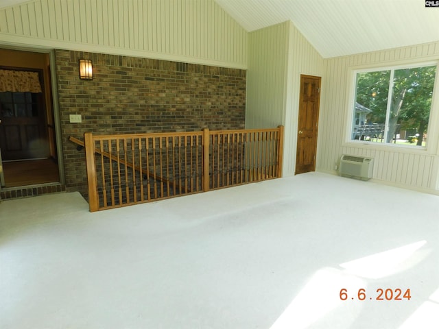 additional living space featuring vaulted ceiling, a wall mounted AC, and brick wall