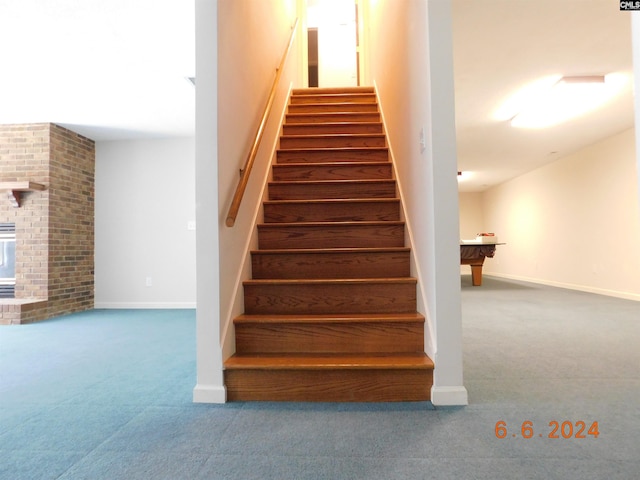 stairs with carpet and a brick fireplace