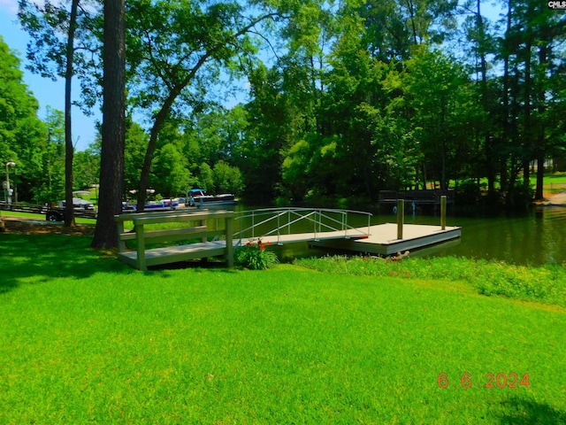 view of community with a lawn, a boat dock, and a water view