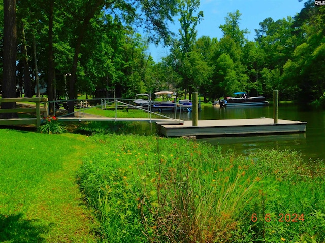 view of home's community with a lawn, a water view, and a boat dock