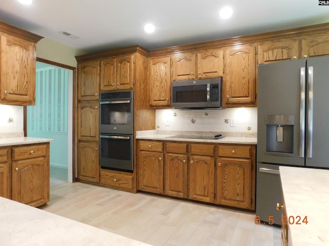 kitchen with backsplash, light hardwood / wood-style flooring, and appliances with stainless steel finishes