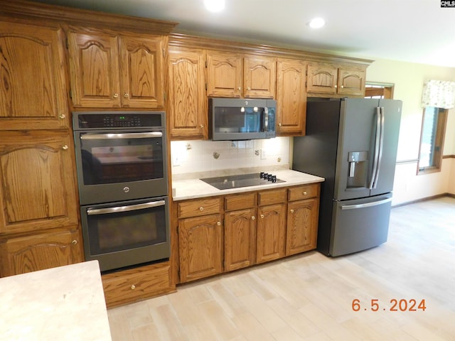 kitchen featuring decorative backsplash, appliances with stainless steel finishes, and light hardwood / wood-style flooring