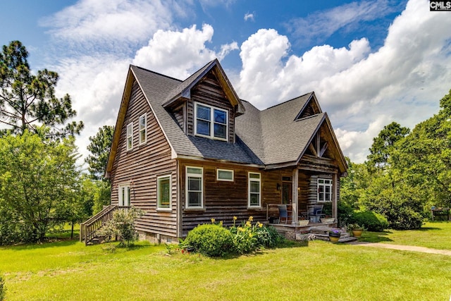 cabin featuring a front lawn and roof with shingles