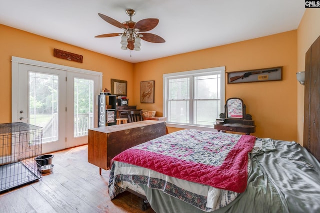 bedroom featuring access to exterior, multiple windows, light wood-style floors, and a ceiling fan