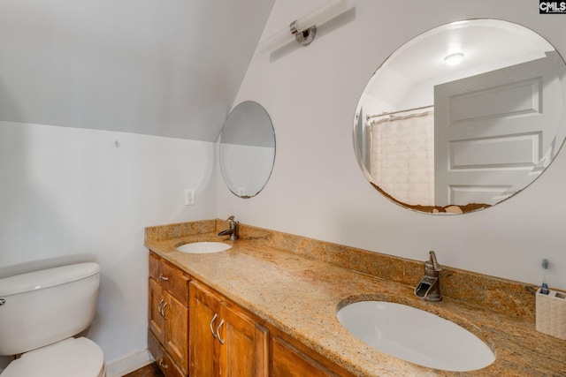 bathroom with lofted ceiling, double vanity, a sink, and toilet