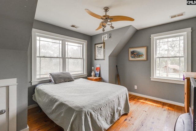 bedroom with light wood finished floors, a ceiling fan, visible vents, and baseboards