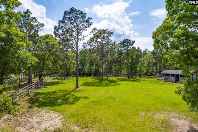 view of yard featuring a rural view, fence, and an outdoor structure