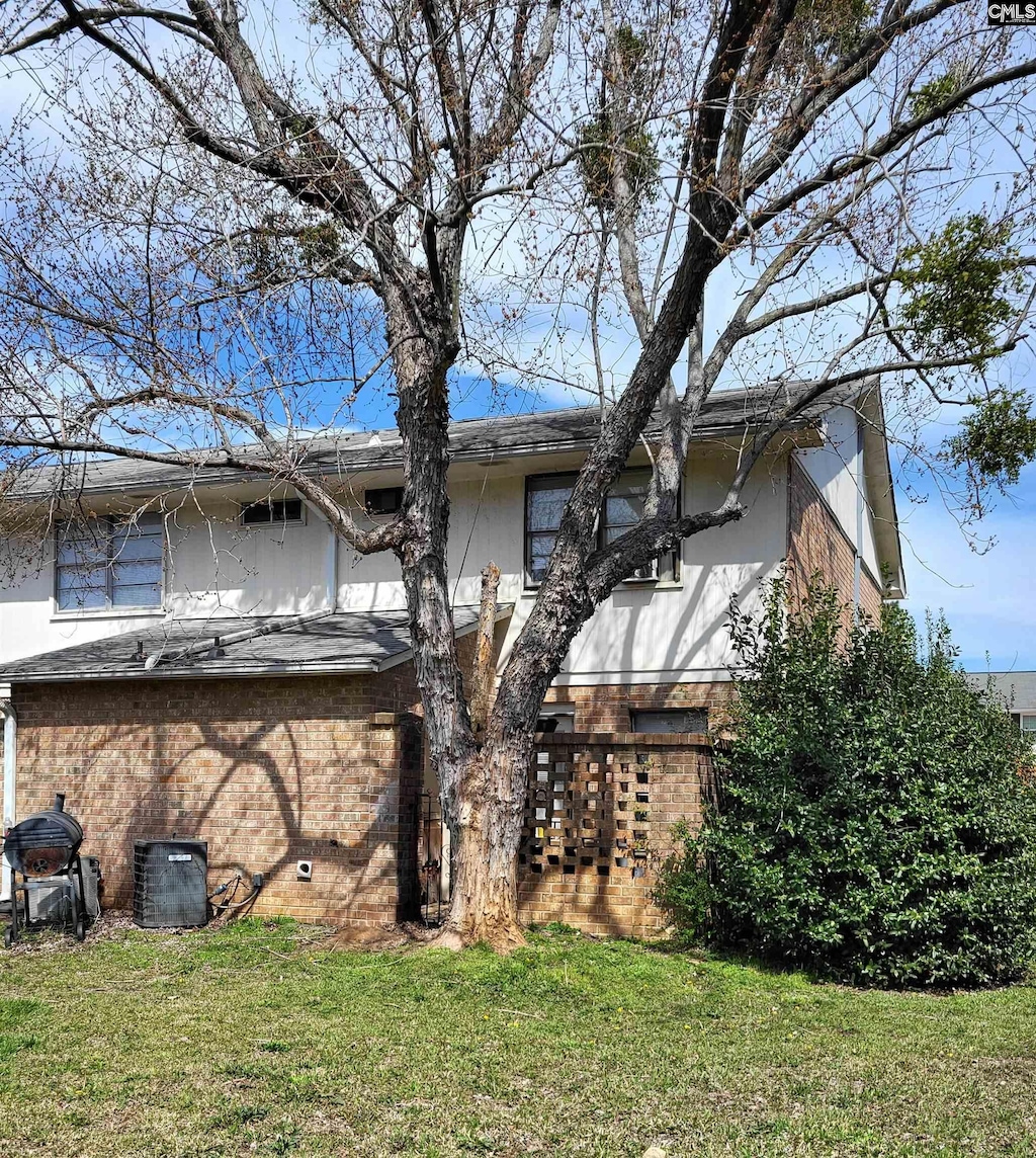 back of house featuring a lawn and central air condition unit