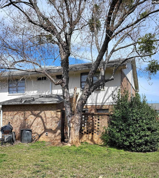 back of house featuring a lawn and central air condition unit