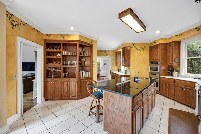 kitchen with crown molding, a kitchen island, a breakfast bar area, sink, and light tile floors