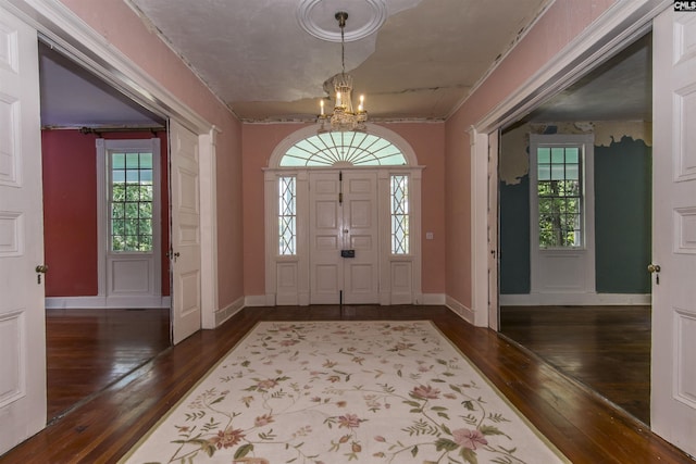 entryway with dark wood-type flooring and a chandelier