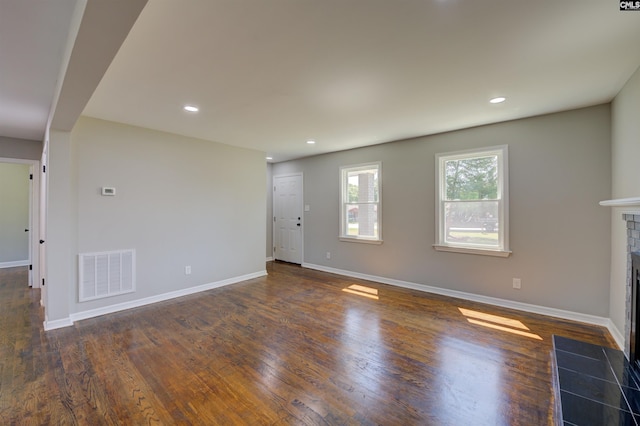 unfurnished room featuring dark hardwood / wood-style floors and a tiled fireplace