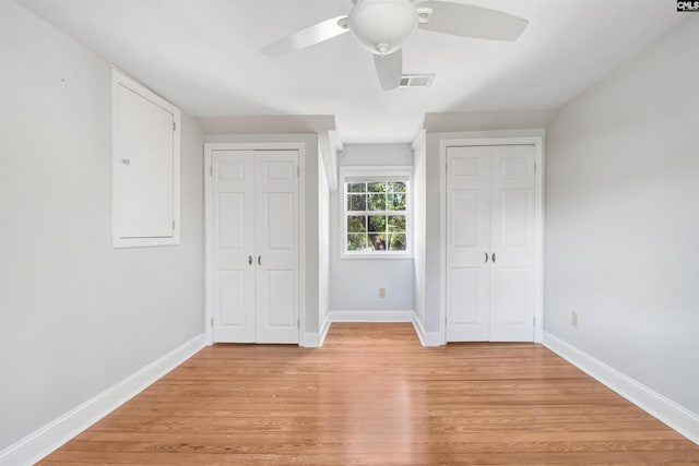 unfurnished bedroom with multiple closets, ceiling fan, and light hardwood / wood-style floors