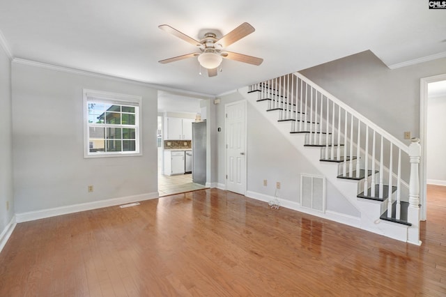 unfurnished living room with ceiling fan, ornamental molding, and light wood-type flooring