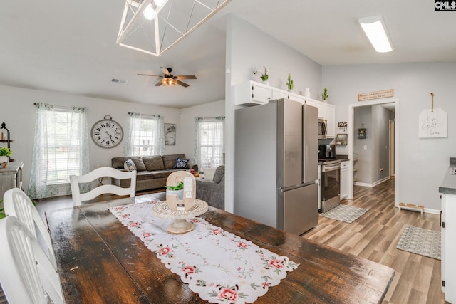 dining room with light wood-type flooring, vaulted ceiling, and ceiling fan