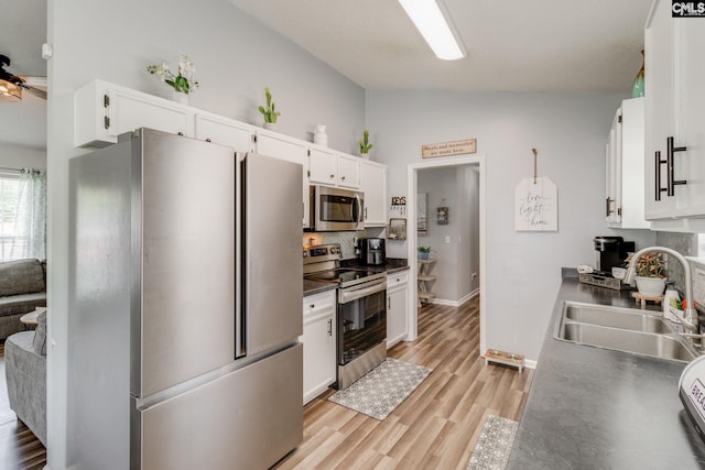 kitchen with sink, light hardwood / wood-style floors, lofted ceiling, white cabinets, and appliances with stainless steel finishes