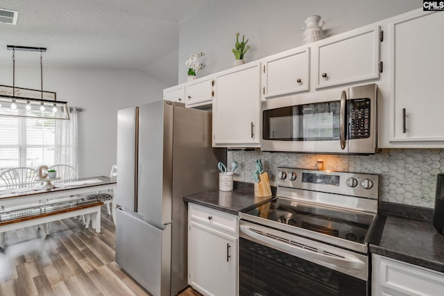 kitchen with tasteful backsplash, white cabinetry, lofted ceiling, and appliances with stainless steel finishes