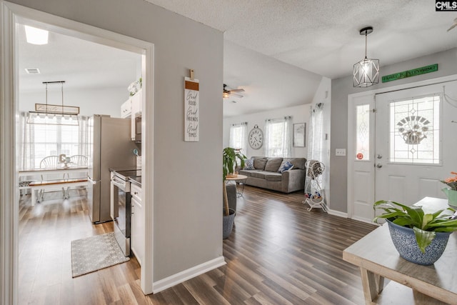 foyer entrance featuring a textured ceiling, ceiling fan, vaulted ceiling, and hardwood / wood-style flooring