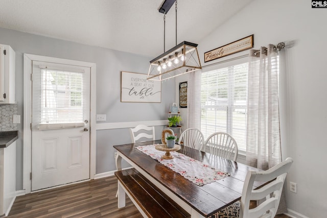 dining area featuring dark hardwood / wood-style floors, an inviting chandelier, and lofted ceiling