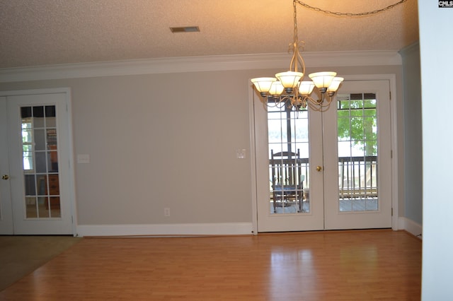 doorway featuring french doors, crown molding, hardwood / wood-style floors, a chandelier, and a textured ceiling