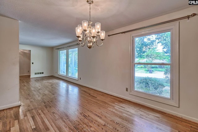 empty room featuring a chandelier and light hardwood / wood-style flooring