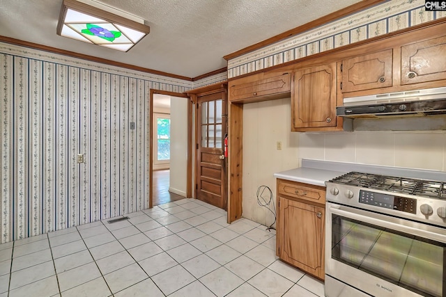 kitchen featuring stainless steel gas stove, a textured ceiling, light tile patterned floors, and crown molding