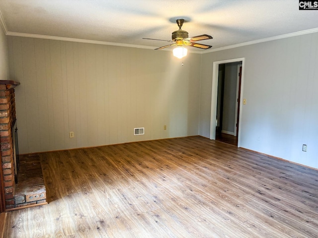 unfurnished room featuring a textured ceiling, wood walls, ceiling fan, light hardwood / wood-style flooring, and crown molding