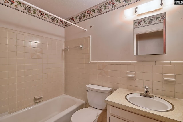 full bathroom featuring toilet, tiled shower / bath, vanity, and tile walls