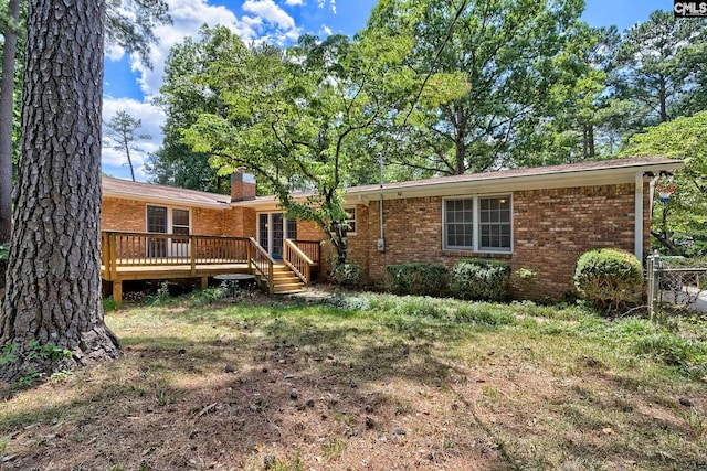 back of property featuring a deck and a lawn