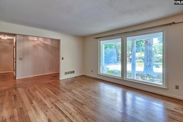 empty room with light hardwood / wood-style floors and a textured ceiling