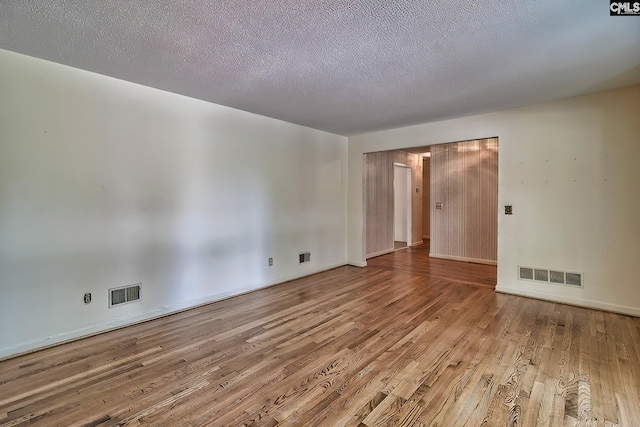 spare room with light hardwood / wood-style floors and a textured ceiling