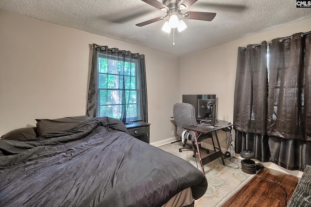 bedroom with hardwood / wood-style floors, ceiling fan, and a textured ceiling