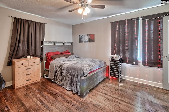 bedroom with a textured ceiling, ceiling fan, and dark wood-type flooring