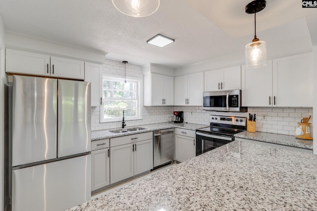 kitchen with sink, stainless steel appliances, white cabinets, and pendant lighting