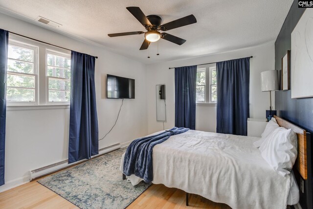 bedroom featuring a baseboard radiator, a textured ceiling, ceiling fan, and hardwood / wood-style flooring