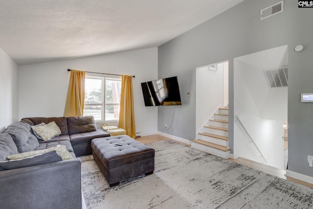 living room with a textured ceiling, baseboard heating, lofted ceiling, and wood-type flooring