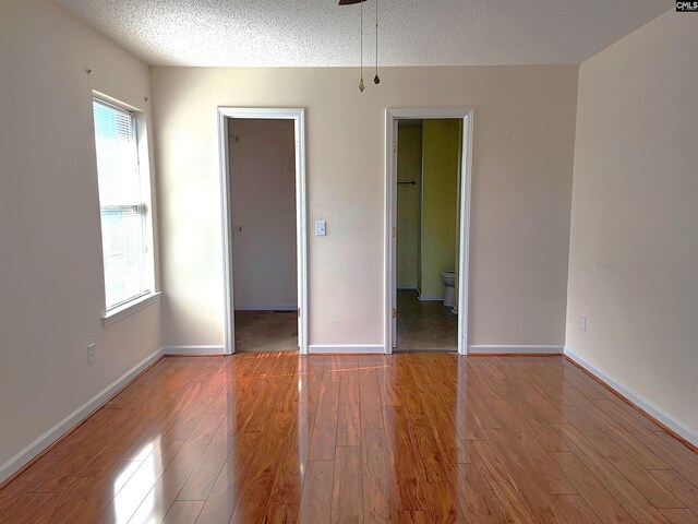 empty room featuring wood-type flooring, a textured ceiling, and plenty of natural light