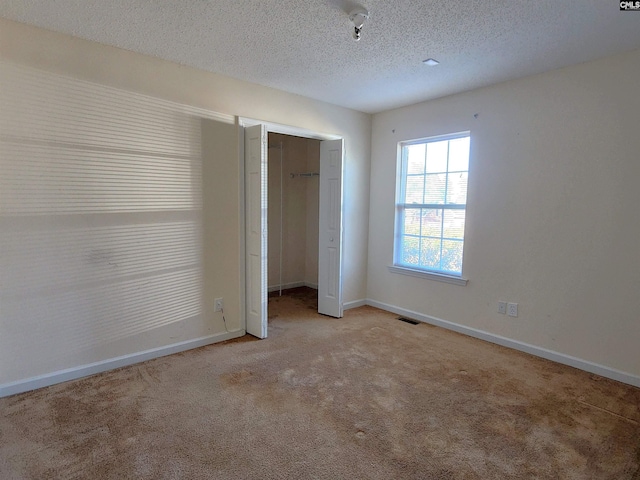 unfurnished bedroom featuring a closet, light carpet, and a textured ceiling